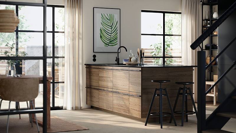 A bright open kitchen with a door to the garden has a large kitchen island with STENSTA fronts in dark brown ash veneer.