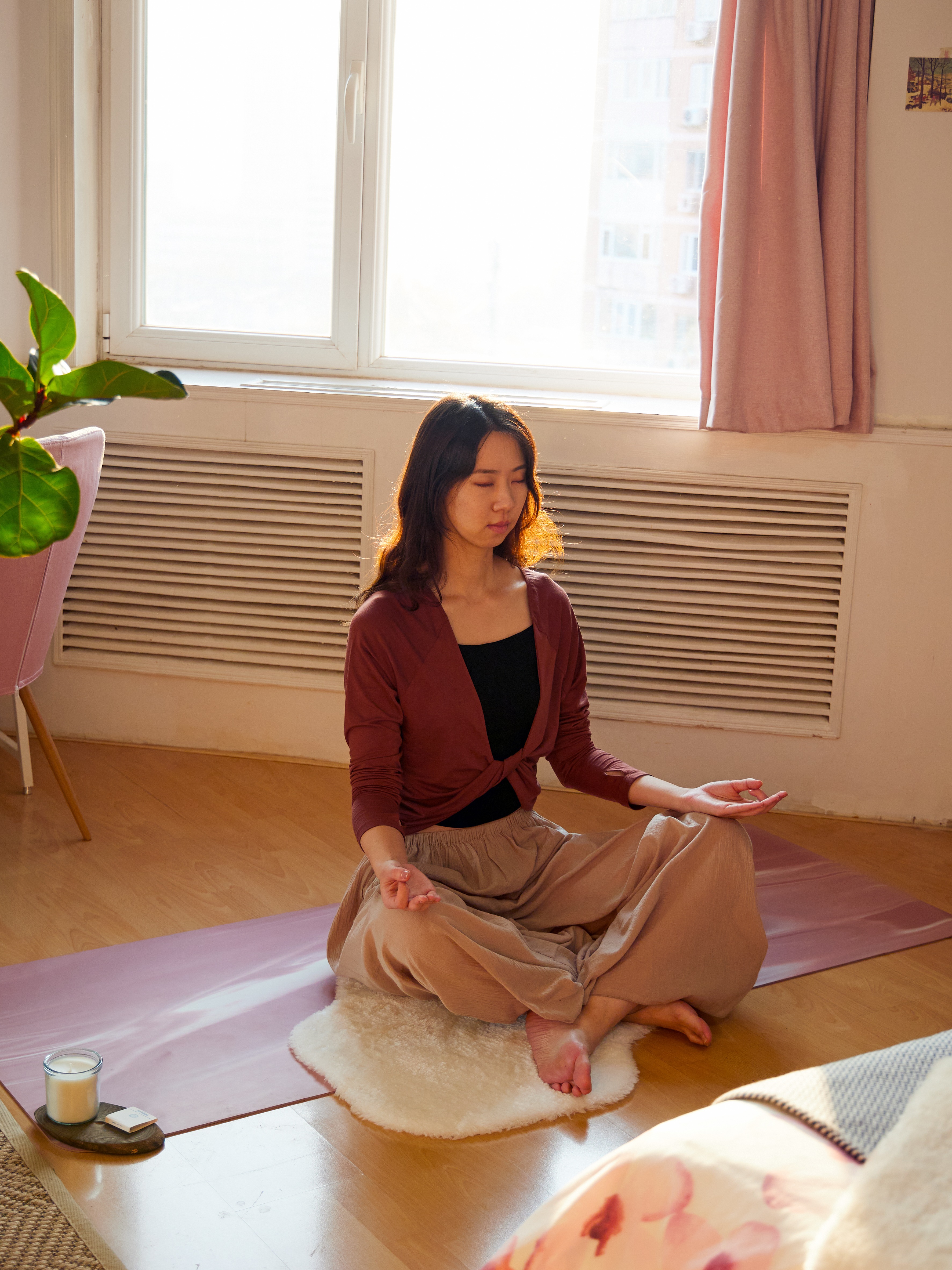 在房间窗前的地板上,一位女士坐在白色TOFTLUND 托夫伦 地毯上冥想。