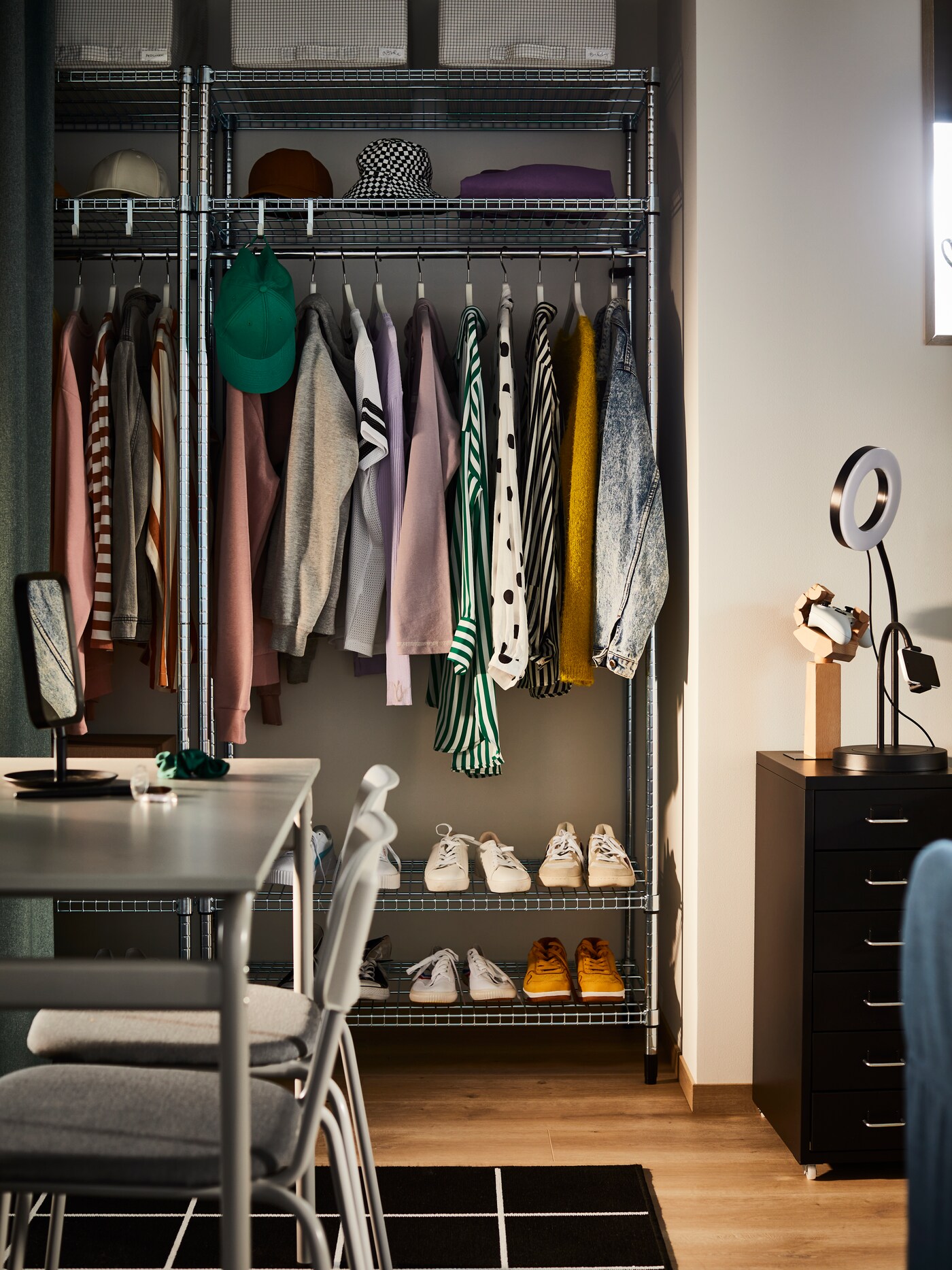 Two OMAR shelving units with clothes rail with colourful clothes hanging on the rails and sneakers on the lower shelves.