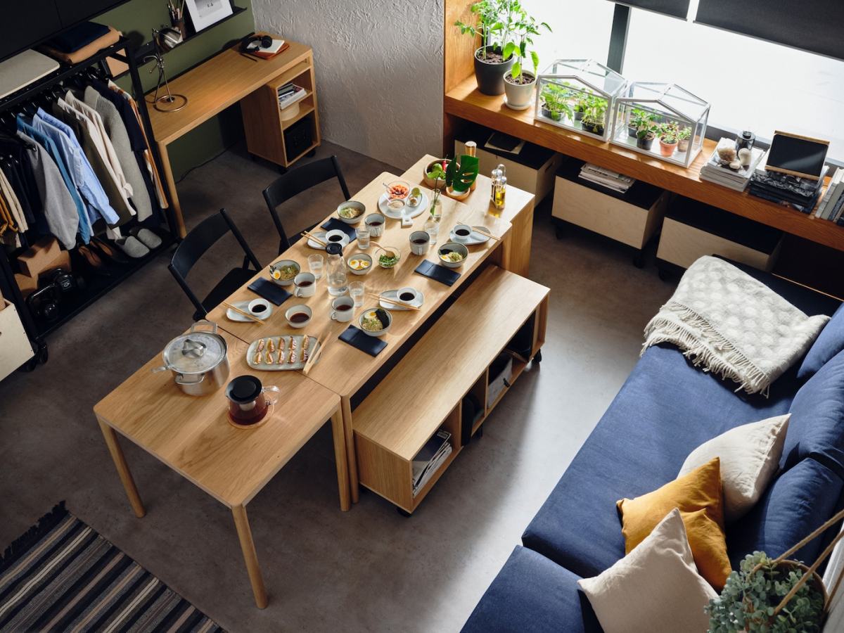 RÅVAROR tables and storage units are combined to create a dining area. There is crockery filled with food on the tables.