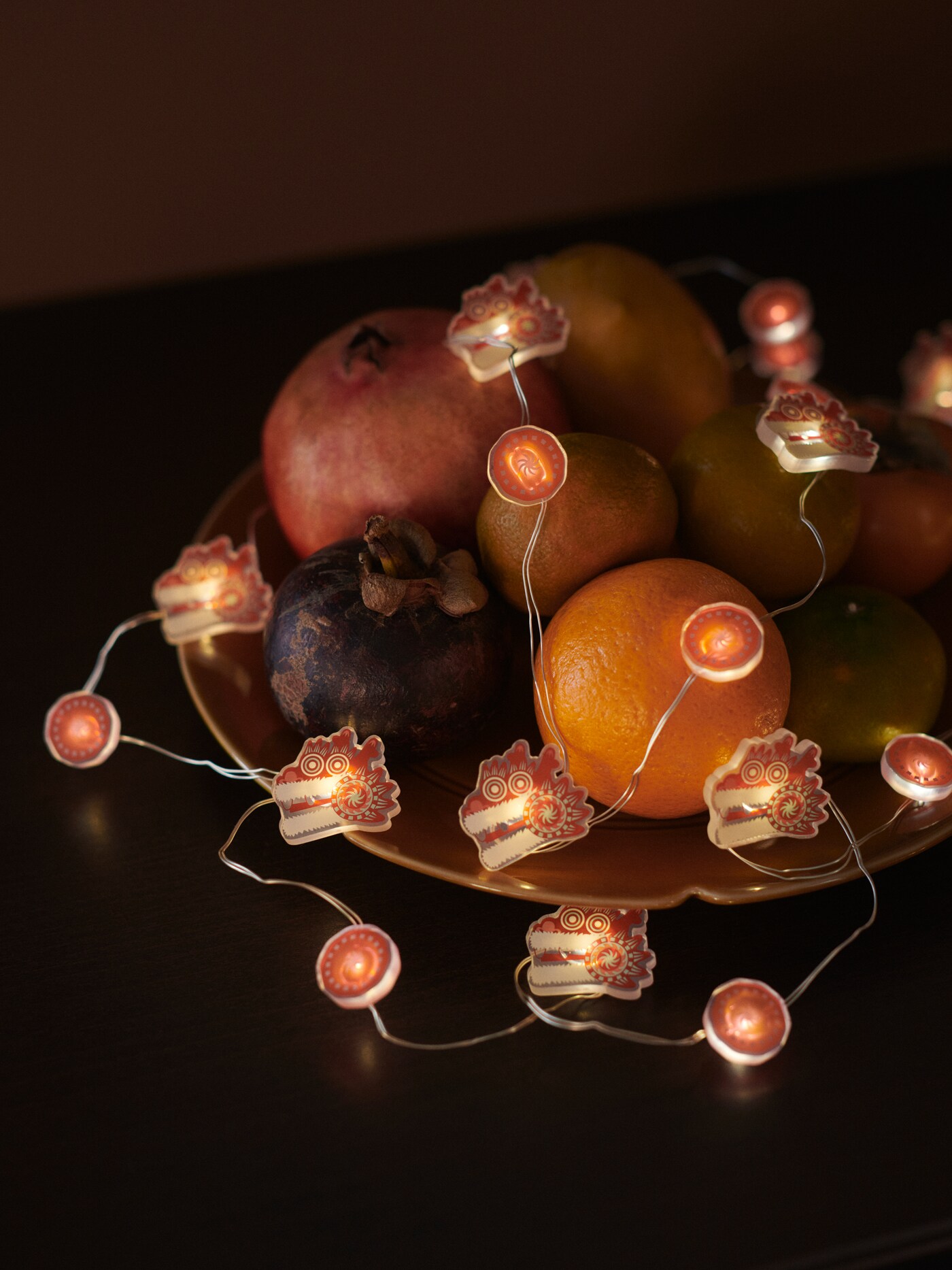 A FÖSSTA LED lighting chain draped over a selection of fruit in a yellow FÖSSTA plate.