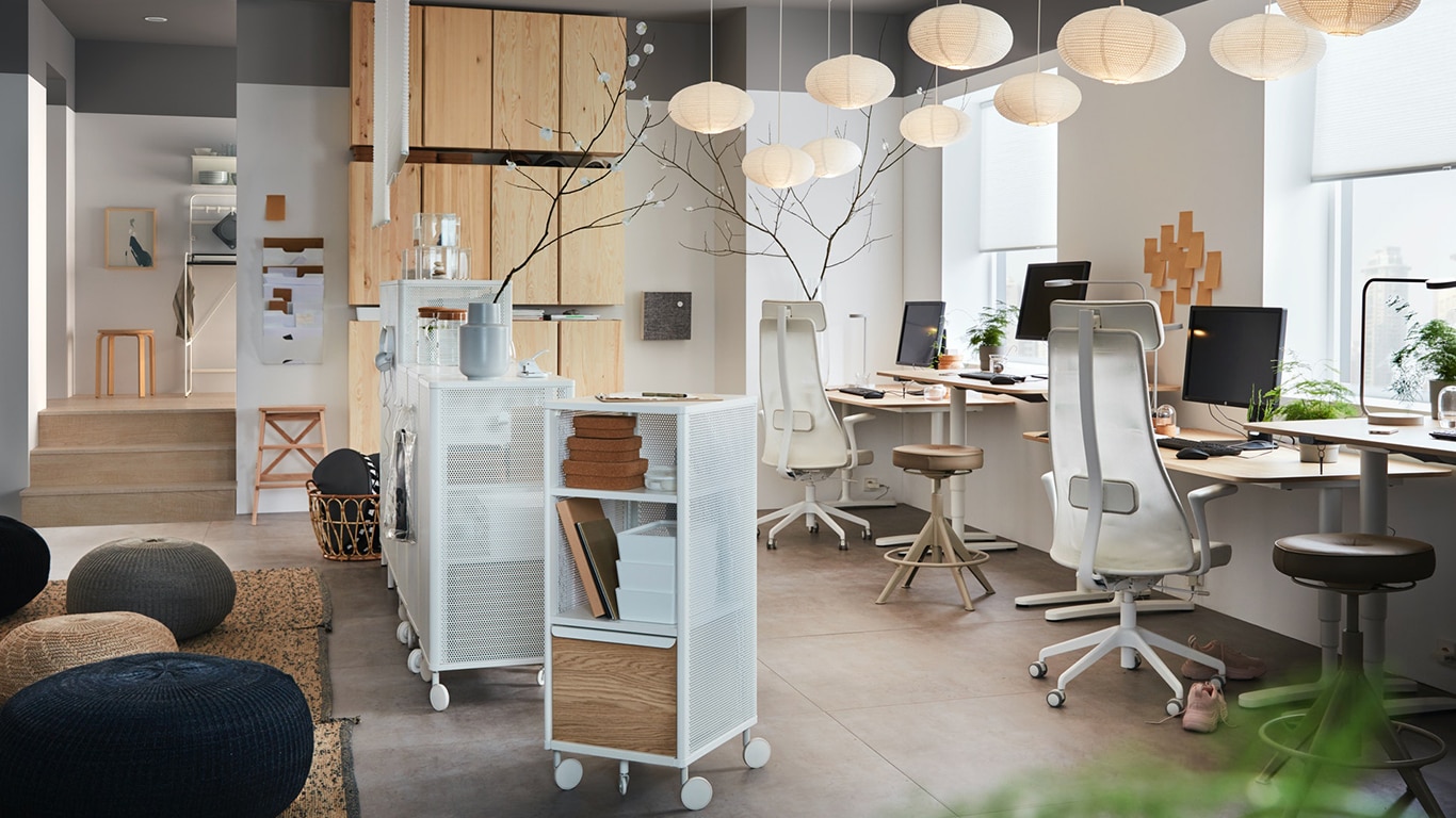 An open-plan office featuring an area with comfy office chairs around desks, drawer units and storage units